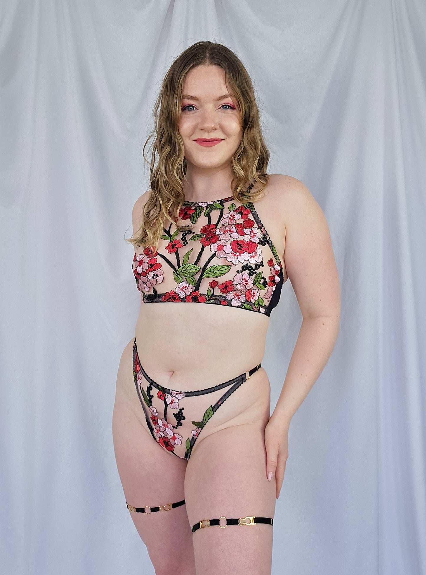 Woman wearing a floral embroidered lingerie set against a plain background